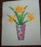 Three cross-stitched daffodils in a vase.